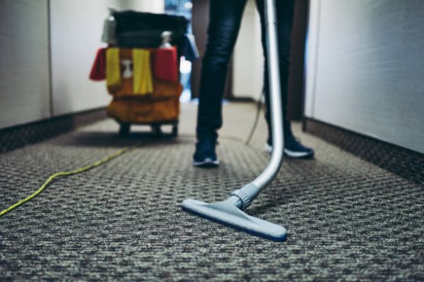Janitor vacuum cleaning the corridor of an office building.